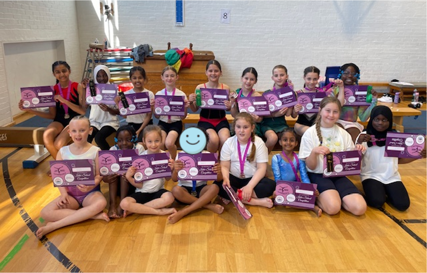 Smiling children hold up their gymnastics certificates